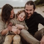 Inverloch family lifestyle photographer Family Beach Session Styling: A joyful family poses on the sandy shore, capturing the essence of relaxed elegance against the backdrop of sun-kissed waves and azure skies.