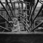 Photography of little girl climbing cattle chute