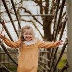 Photography of little girl smiling on cattle chute