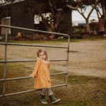Photography of little girl waiting for parents holding fence